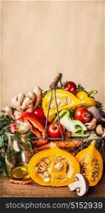 Basket with various autumn seasonal organic harvest vegetables and pumpkin at wall background, front view, vertical. Autumn food inspiration