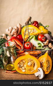 Basket with various autumn seasonal organic harvest vegetables and pumpkin at wall background, front view. Autumn food inspiration