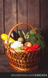 Basket with vegetables and fresh herbs on the wood background