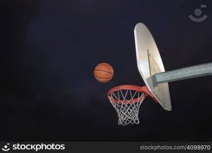 Basketball going into the hoop at an outdoor court in the dark