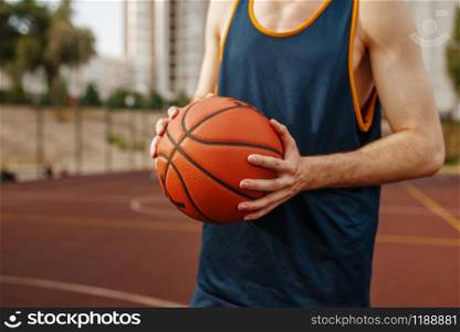 Basketball player aiming for the throw on outdoor court. Male athlete in sportswear holds ball on streetball training. Basketball player aiming for throw, outdoor court