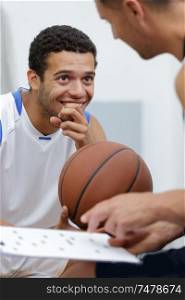basketball player laughing while the coach is talking