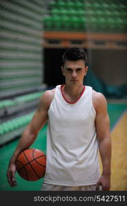 Basketball player portrait on basketball court holding ball with black isolated background