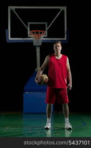 Basketball player portrait on basketball court holding ball with black isolated background