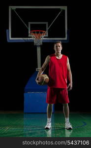 Basketball player portrait on basketball court holding ball with black isolated background