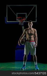 Basketball player portrait on basketball court holding ball with black isolated background