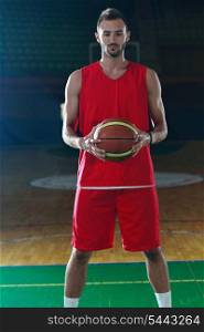 Basketball player portrait on basketball court holding ball with black isolated background