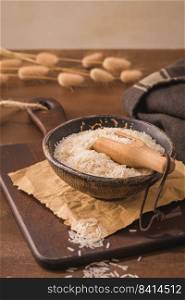Basmati rice in ceramic bowl with wooden scoop on rustic countertop.