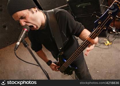 Bassist playing and screaming into a microphone.