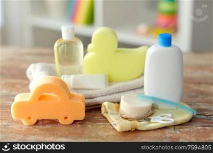 bath time and care products concept - baby accessories for bathing on wooden table at home. baby accessories for bathing on wooden table