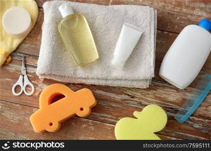 bath time and care products concept - baby accessories for bathing on wooden table at home. baby accessories for bathing on wooden table