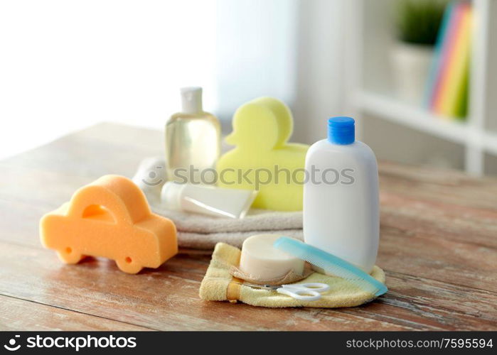 bath time and care products concept - baby accessories for bathing on wooden table at home. baby accessories for bathing on wooden table