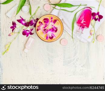 Bath with pink orchid , towel, cream and lotion with water bowl on white shabby chic background, top view. Spa or wellness concept