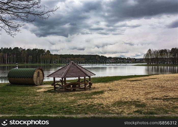 Bathhouse and gazebo on the shore near the forest lake
