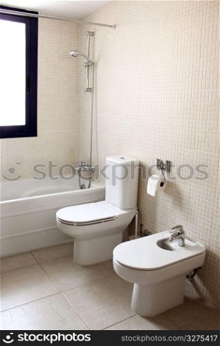 bathroom with bath toilet and bidet window natural light cream color
