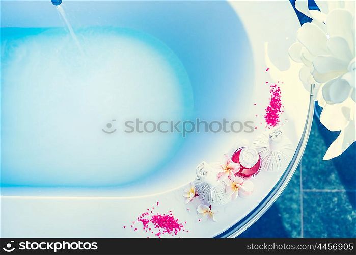 Bathtub with blue water , body care products and frangipani flowers. Spa or Wellnes backgrounds