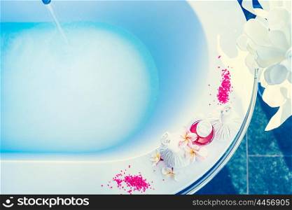 Bathtub with blue water , body care products and frangipani flowers. Spa or Wellnes backgrounds
