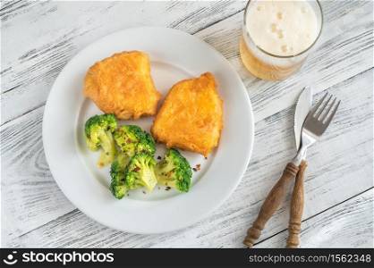 Battered fish with steamed broccoli and glass of beer