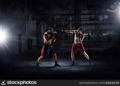 Battle of two boxers. Strong boxers fighting in dark industrial interior mixed media