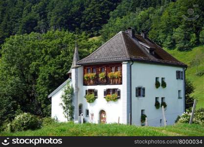 BAUEN, SWITZERLAND - CIRCA AUGUST 2015 White farm house and mountaiin