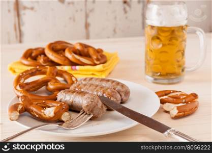 Bavarian cooked sausage and pretzel on background with a glass of beer. Bavarian cooked sausage and pretzel