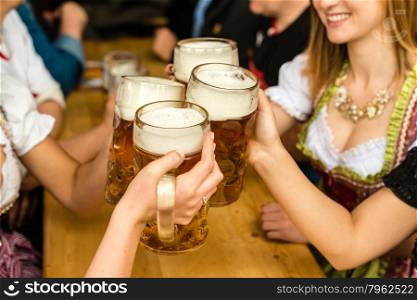 Bavarian girls in traditional Dirndl dresses are drinking beer and having fun at the Oktoberfest. Bavarian girls drinking beer