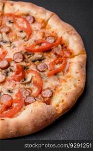 Bavarian pizza with smoked sausages, tomatoes, cheese, salt and spices on a dark concrete background