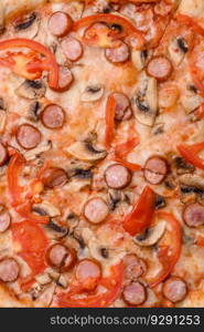 Bavarian pizza with smoked sausages, tomatoes, cheese, salt and spices on a dark concrete background