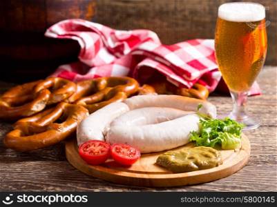 bavarian white sausages with pretzel and glass of beer on wooden table