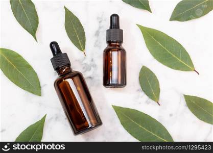 Bay laurel essential oil on marble table. Bay oil on glass bottle with dropper. Laurus nobilis