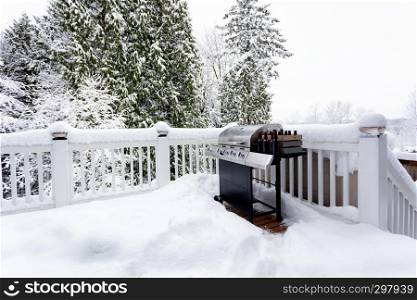 BBQ cooker with bottles of beer during winter time on home outdoor deck