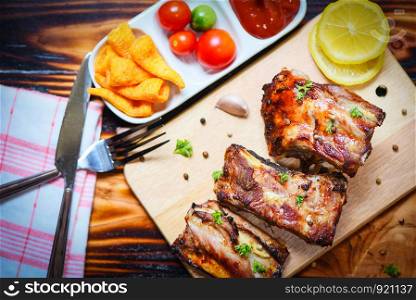 bbq pork ribs grilled with tomatoes ketchup and herbs spices served on the table / Roasted barbecue pork spare rib sliced