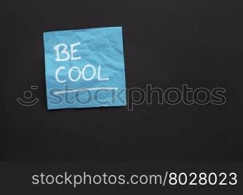Be cool reminder - white marker handwriting on a sticky note against black paper background