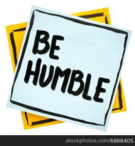Be humble advice or reminder - handwriting in black ink on an isolated sticky note