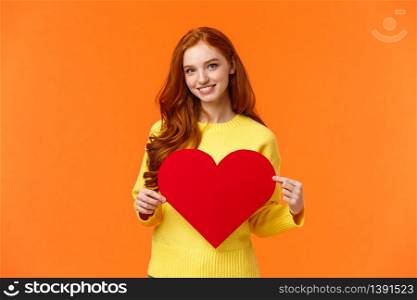 Be my valentine. Lovely gorgeous redhead curly silly girlfriend holding large heart sign and smiling, waiting for valentines day holiday to express love, standing orange background cute.. Be my valentine. Lovely gorgeous redhead curly silly girlfriend holding large heart sign and smiling, waiting for valentines day holiday to express love, standing orange background cute