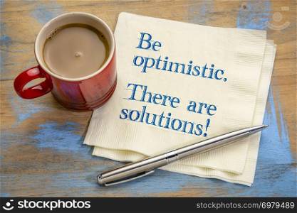 Be optimistic. There are solutions. Inspiraitonal handwriting on napkin with a cup of coffee.