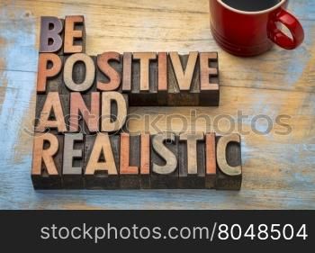 be positive and realistic - motivational text in vintage letterpress wood type printing blocks