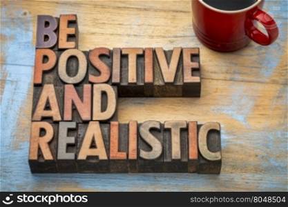 be positive and realistic - motivational text in vintage letterpress wood type printing blocks
