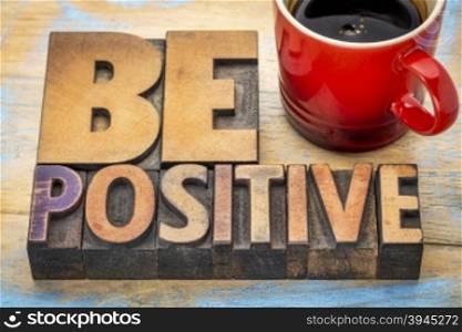 be positive banner in vintage letterpress wood type blocks stained by color inks with a cup of coffee