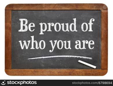 Be proud of who you are - white chalk text on a vintage slate blackboard