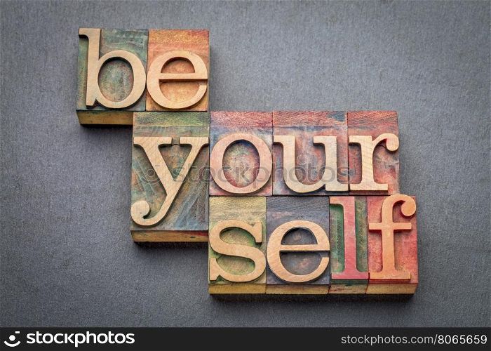 be yourself word abstract in letterpress wood type blocks against gray slate stone