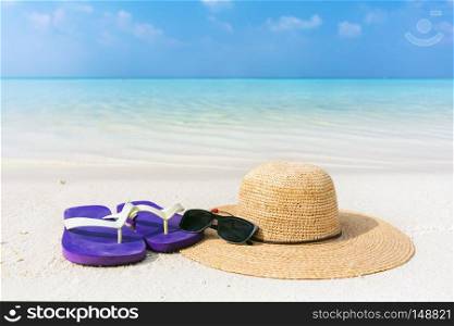 Beach accessories on sand, clear turquoise ocean in Maldives. Vacation, travel concept. Sunglasses, flip-flops and sunhat. Beach accessories on sand, clear turquoise ocean in Maldives
