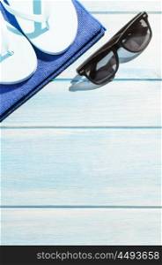 beach accessories on table. beach accessories. stylish sunglasses with towel and flip flops on blue wooden table