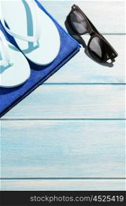 beach accessories on table. beach accessories. stylish sunglasses with towel and flip flops on blue wooden table