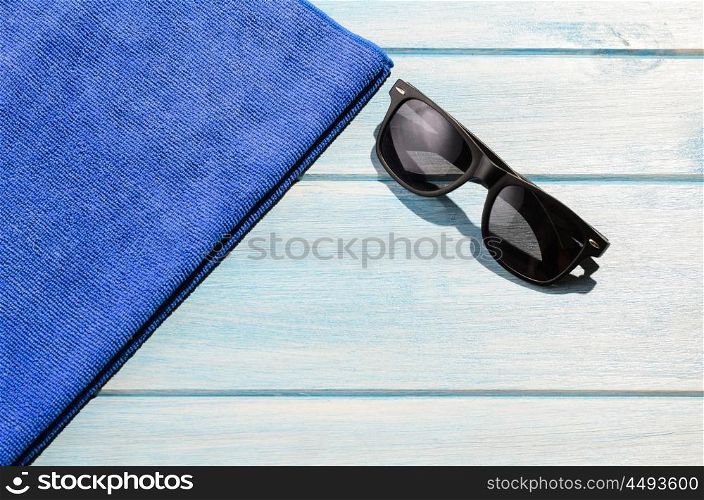 beach accessories on table. beach accessories. stylish sunglasses with towel on blue wooden table