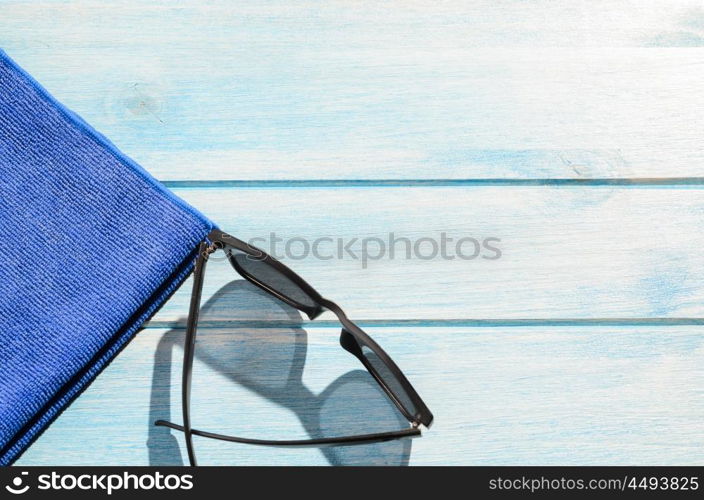 beach accessories on table. beach accessories. stylish sunglasses with towel on blue wooden table