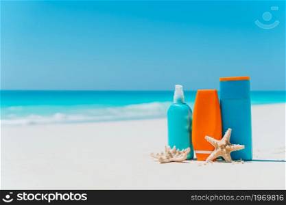 Beach accessories on the beach. Suncream bottles, sunglasses, starfish on white sandy beach