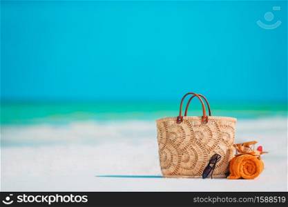 Beach accessories - toy plane, straw bag, orange towel and unglasses on the beach. Beach accessories - bag, straw hat, sunglasses on white beach