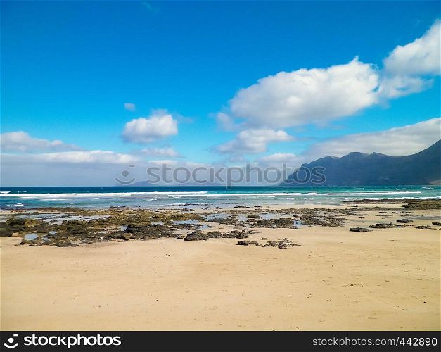 Beach and Mountains - beautiful coast in Caleta de Famara, Lanzarote Canary Islands. Beach in Caleta de Famara is very popular among surfers.. Beach and mountains - beautiful coast in Caleta de Famara, Lanzarote Canary Islands.