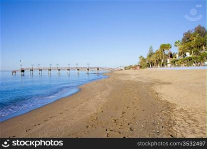 Beach and pier on Costa del Sol between resort town of Marbella and Puerto Banus in Spain, Malaga province.